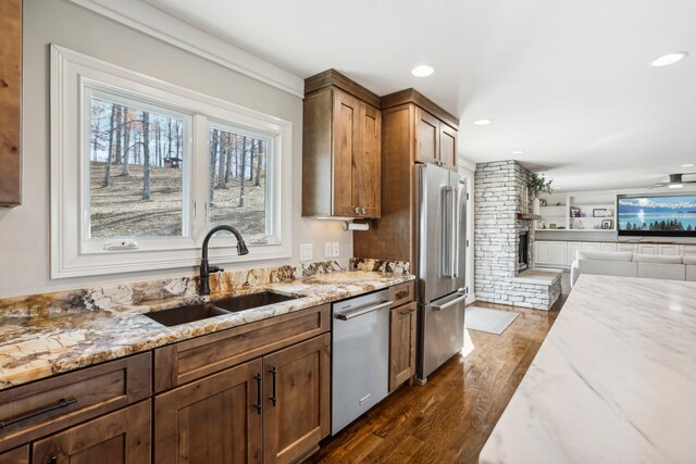 kitchen with dark hardwood / wood-style flooring, light stone counters, sink, and stainless steel appliances