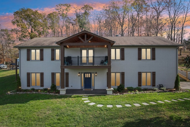 view of front of property featuring a balcony and a yard