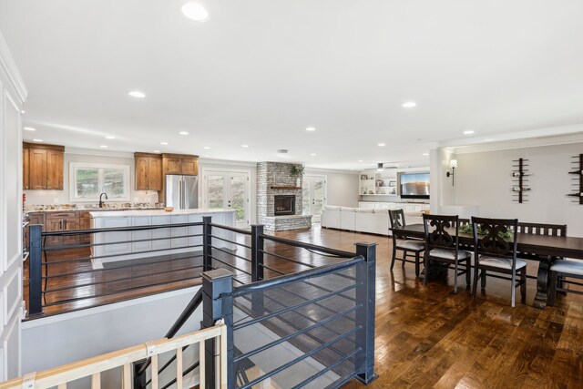 interior space featuring stainless steel refrigerator, sink, dark wood-type flooring, crown molding, and a fireplace