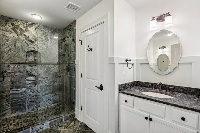 bathroom with a tile shower and vanity