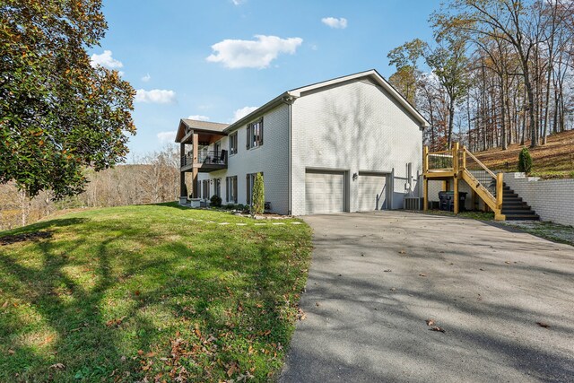 view of side of home featuring a yard, a balcony, and a garage