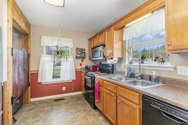 kitchen with black appliances, brown cabinetry, a sink, and visible vents