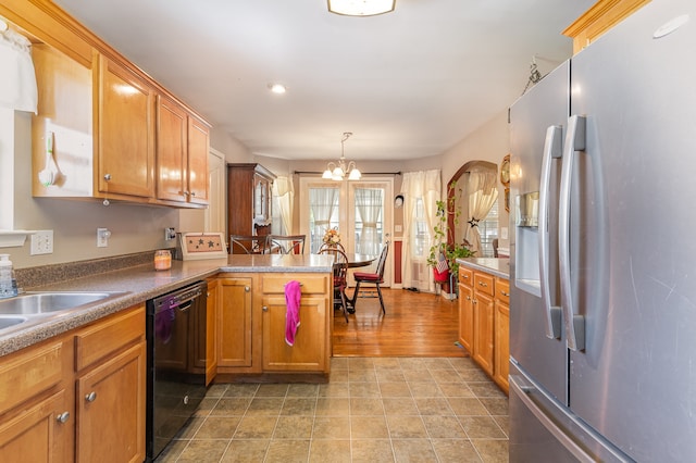 kitchen featuring brown cabinetry, dishwasher, stainless steel fridge with ice dispenser, decorative light fixtures, and a notable chandelier