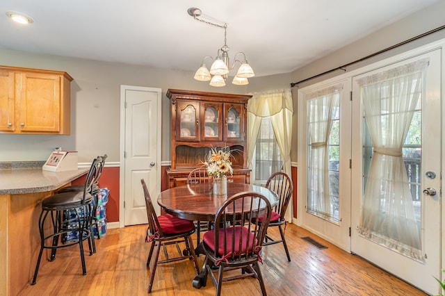 dining space with light wood-type flooring, an inviting chandelier, and visible vents