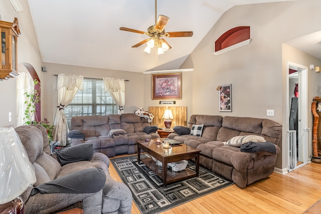 living room featuring ceiling fan, high vaulted ceiling, arched walkways, and wood finished floors