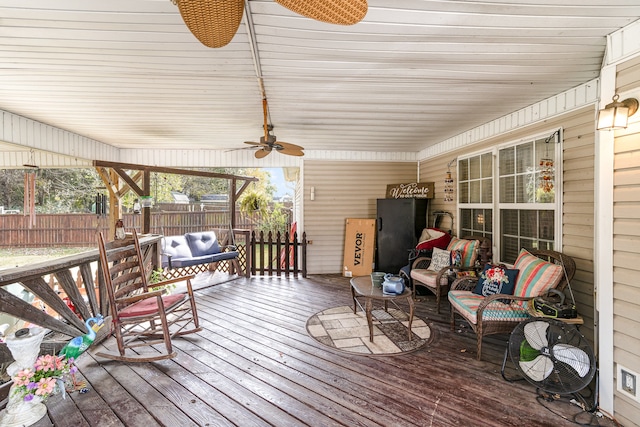 wooden deck with an outdoor hangout area, fence, and a ceiling fan