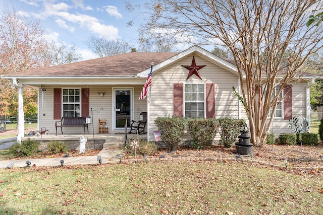 view of front of home featuring covered porch, a shingled roof, and a front yard