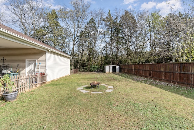 view of yard with an outdoor fire pit, a fenced backyard, an outbuilding, and a storage shed