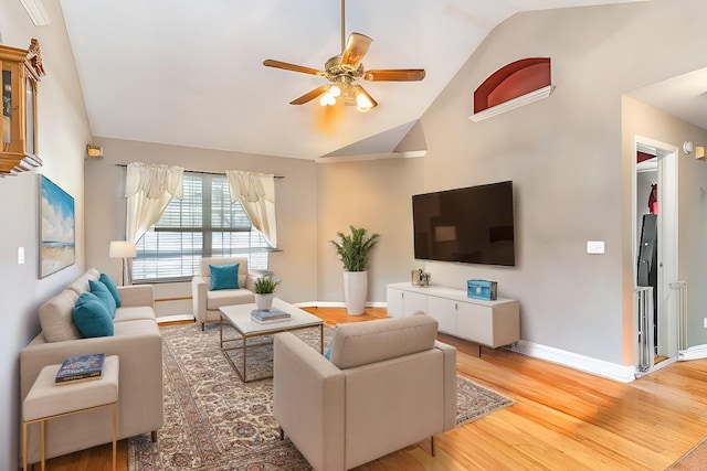 living area with high vaulted ceiling, light wood-style flooring, baseboards, and ceiling fan