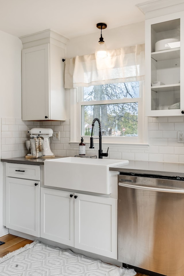 kitchen featuring sink, tasteful backsplash, stainless steel dishwasher, light hardwood / wood-style flooring, and white cabinets