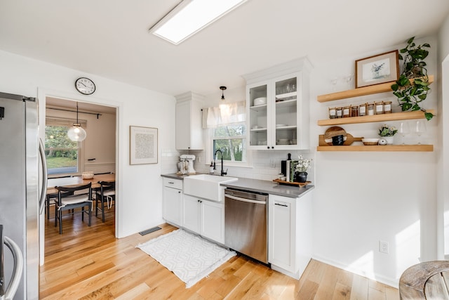 kitchen with stainless steel appliances, light wood-type flooring, white cabinetry, pendant lighting, and sink