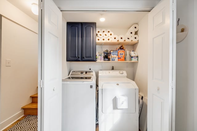 laundry room with separate washer and dryer and cabinets