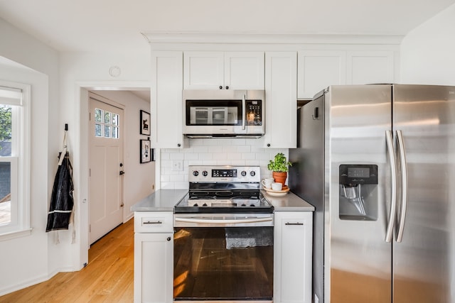 kitchen featuring light hardwood / wood-style flooring, white cabinets, decorative backsplash, and stainless steel appliances