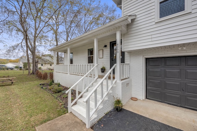 entrance to property featuring a lawn, a garage, and covered porch