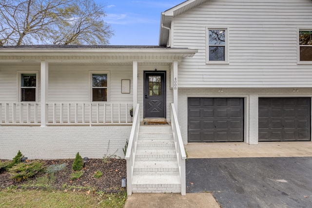 doorway to property with a garage and a porch