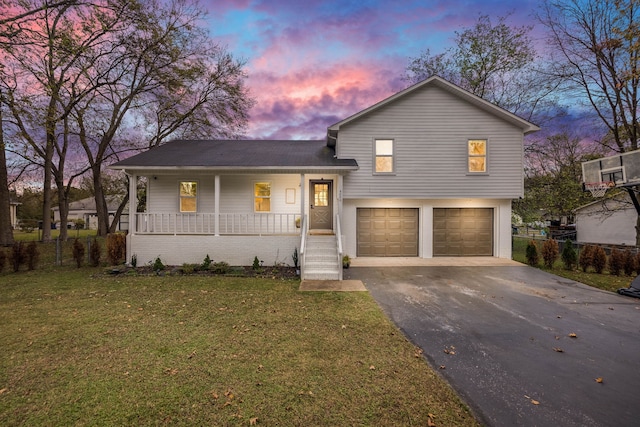 tri-level home featuring a garage, a porch, and a lawn