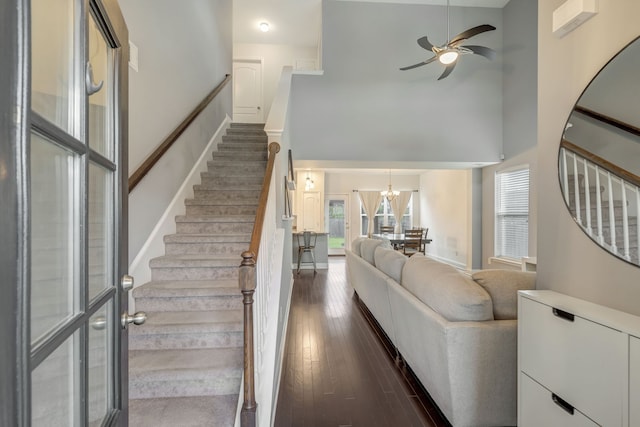 stairway featuring ceiling fan with notable chandelier, hardwood / wood-style flooring, and a high ceiling