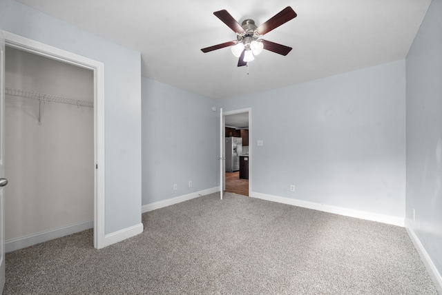 unfurnished bedroom with carpet flooring, stainless steel refrigerator with ice dispenser, ceiling fan, and a closet