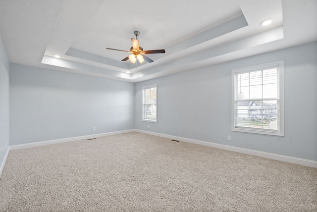 carpeted spare room with ceiling fan and a raised ceiling