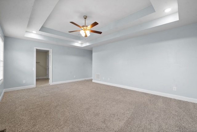 spare room with carpet floors, ceiling fan, and a raised ceiling