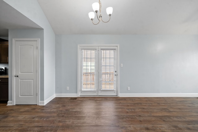 empty room with dark hardwood / wood-style flooring, an inviting chandelier, and lofted ceiling