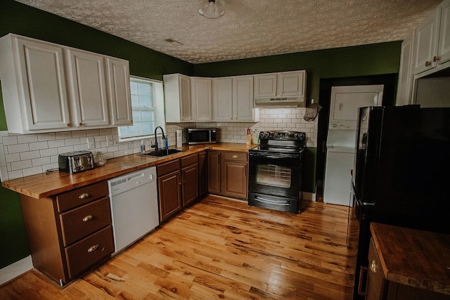 kitchen featuring white cabinets, butcher block countertops, stacked washer and clothes dryer, and black appliances