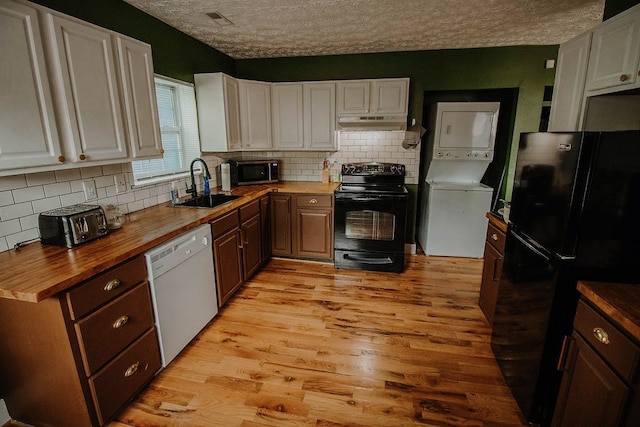 kitchen with stacked washer and clothes dryer, black appliances, a textured ceiling, wood counters, and white cabinetry