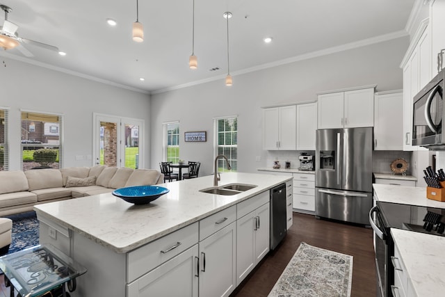 kitchen with stainless steel appliances, white cabinets, sink, and a kitchen island with sink