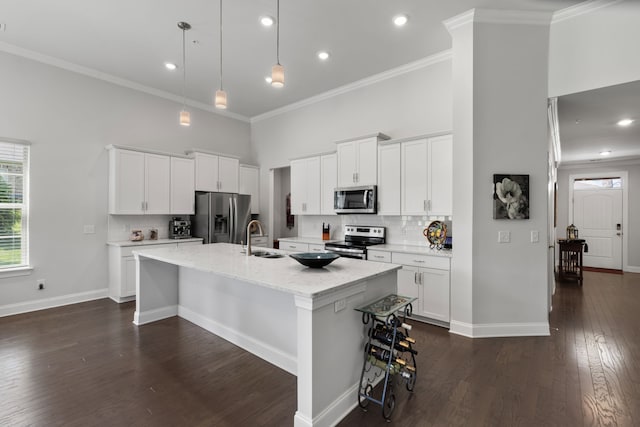 kitchen featuring white cabinets, stainless steel appliances, dark wood-type flooring, and an island with sink