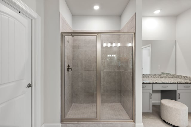 bathroom featuring a shower with door, vanity, and tile patterned flooring