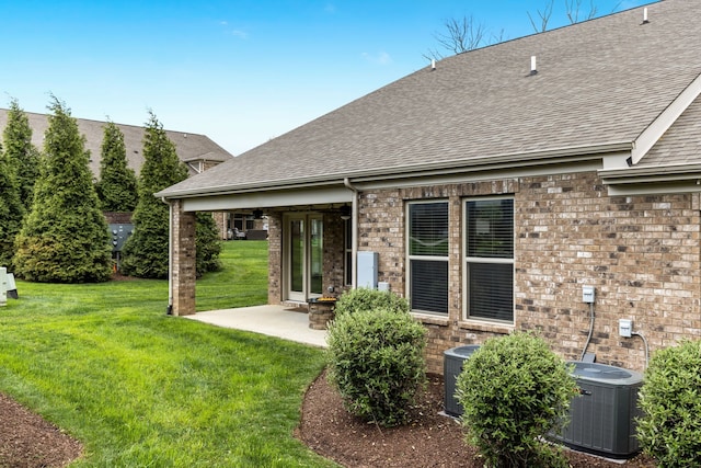 rear view of property featuring cooling unit, a lawn, and a patio