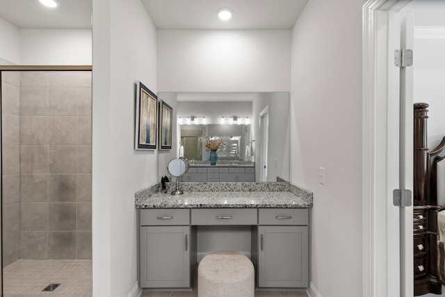 bathroom with tile patterned flooring, vanity, and a tile shower