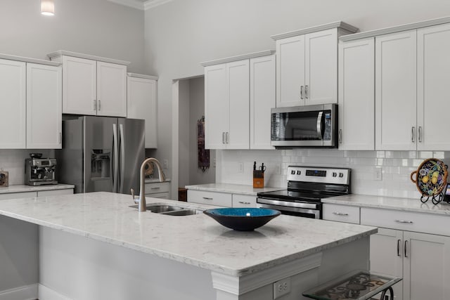 kitchen with white cabinetry, appliances with stainless steel finishes, a kitchen island with sink, and sink