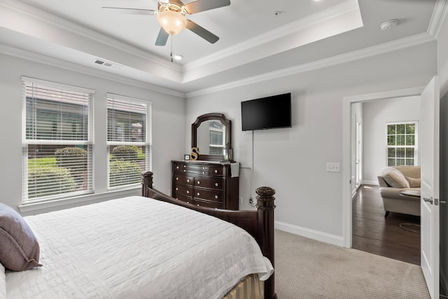 bedroom with ceiling fan, a tray ceiling, crown molding, and wood-type flooring