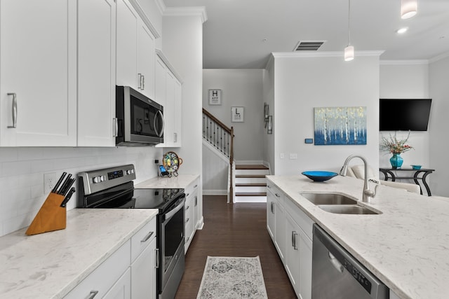 kitchen featuring appliances with stainless steel finishes, decorative light fixtures, dark hardwood / wood-style flooring, sink, and white cabinets