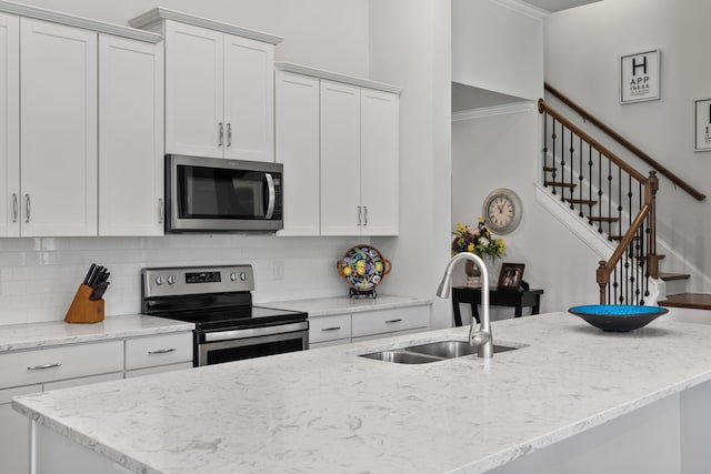 kitchen with white cabinetry, appliances with stainless steel finishes, backsplash, light stone countertops, and sink