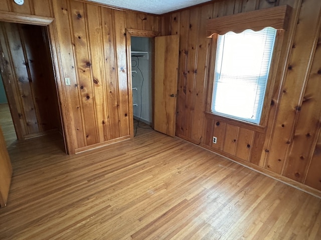 unfurnished bedroom with wood walls, light wood-type flooring, and a closet