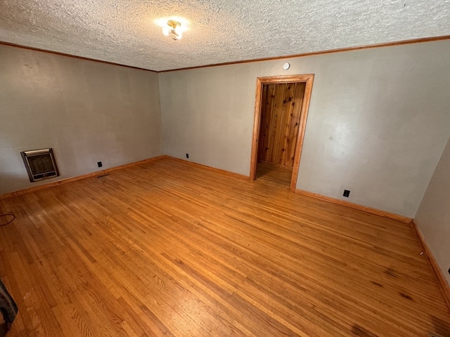 unfurnished room with ornamental molding, light wood-type flooring, a textured ceiling, and heating unit