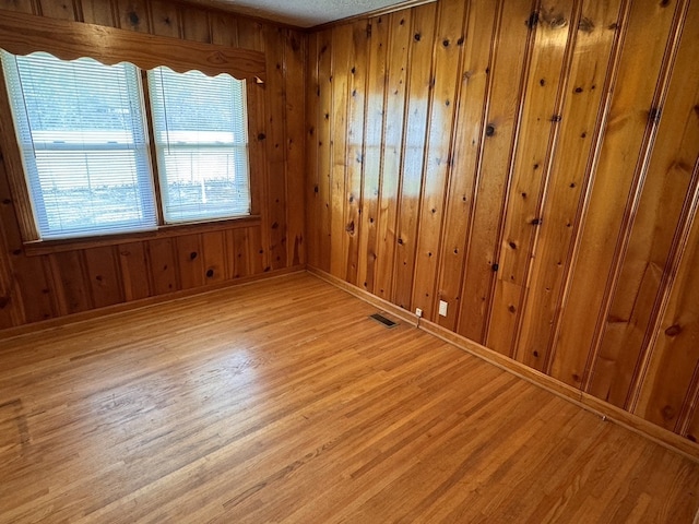 unfurnished room featuring light hardwood / wood-style flooring and wood walls