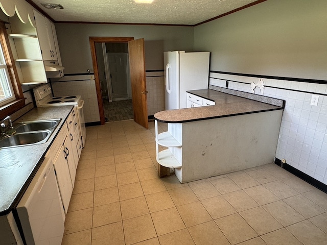 kitchen featuring white appliances, a textured ceiling, sink, and tile walls