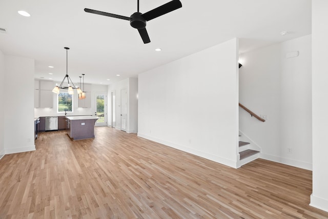 unfurnished living room with ceiling fan, sink, and light wood-type flooring