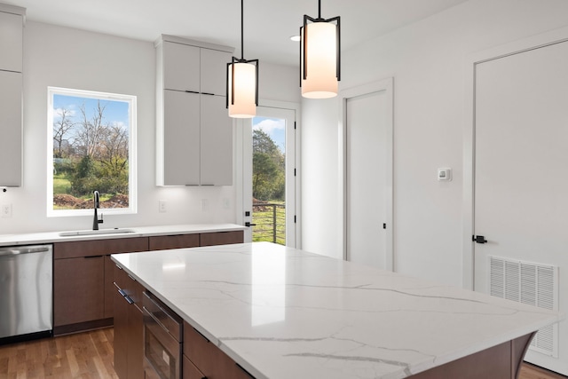 kitchen with stainless steel dishwasher, hanging light fixtures, a healthy amount of sunlight, and sink