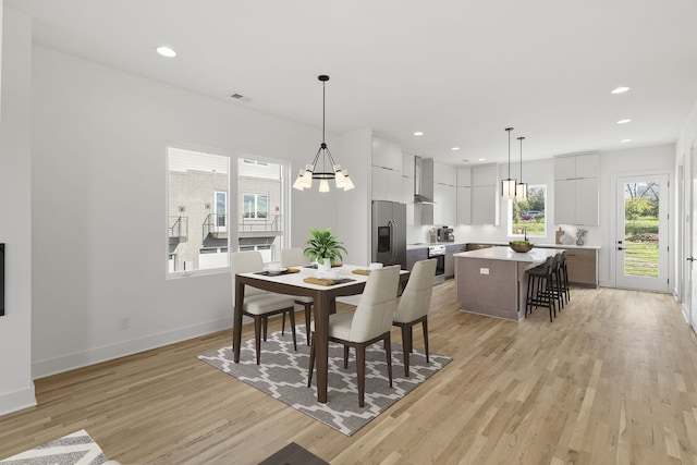 dining space with a healthy amount of sunlight, a notable chandelier, and light hardwood / wood-style floors