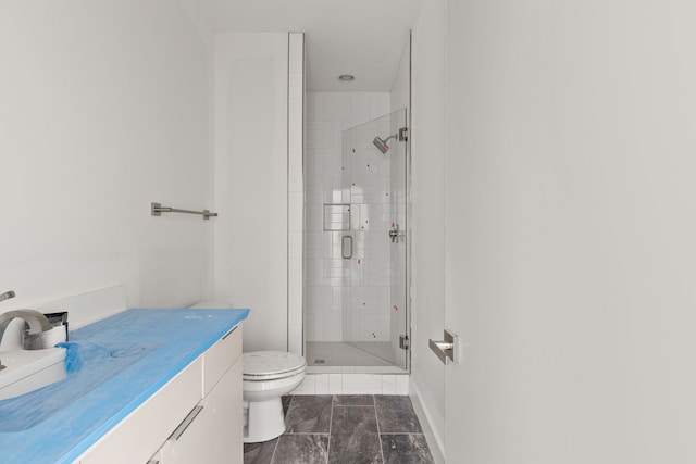 bathroom featuring toilet, vanity, and a shower with shower door