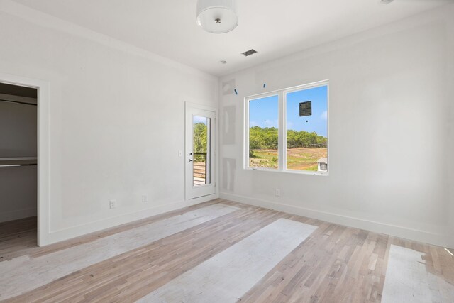 unfurnished bedroom with light hardwood / wood-style floors and a walk in closet