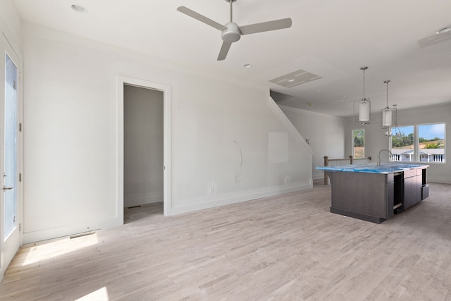 kitchen with ceiling fan, light wood-type flooring, dark brown cabinets, a kitchen island with sink, and pendant lighting