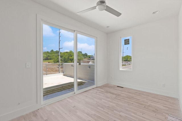 spare room with plenty of natural light, ceiling fan, and light hardwood / wood-style flooring