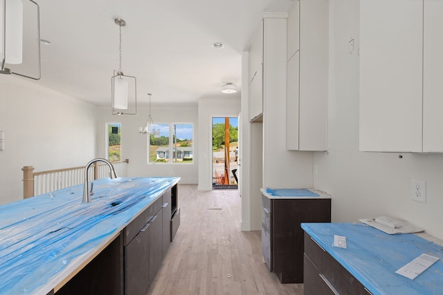 kitchen with white cabinets, light wood-type flooring, dark brown cabinetry, and pendant lighting