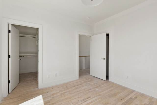 unfurnished bedroom with light wood-type flooring, a walk in closet, and a closet