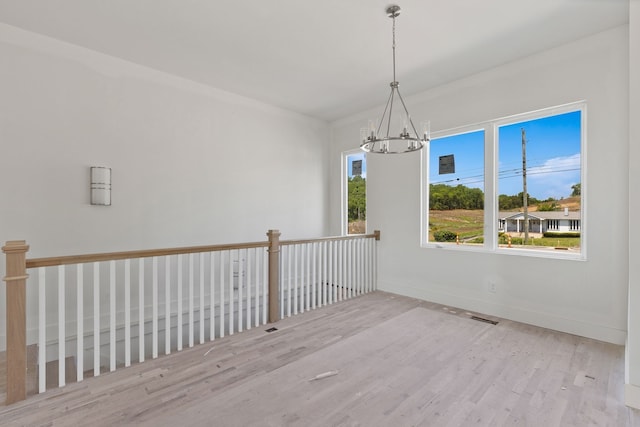 unfurnished room featuring light wood-type flooring and a notable chandelier